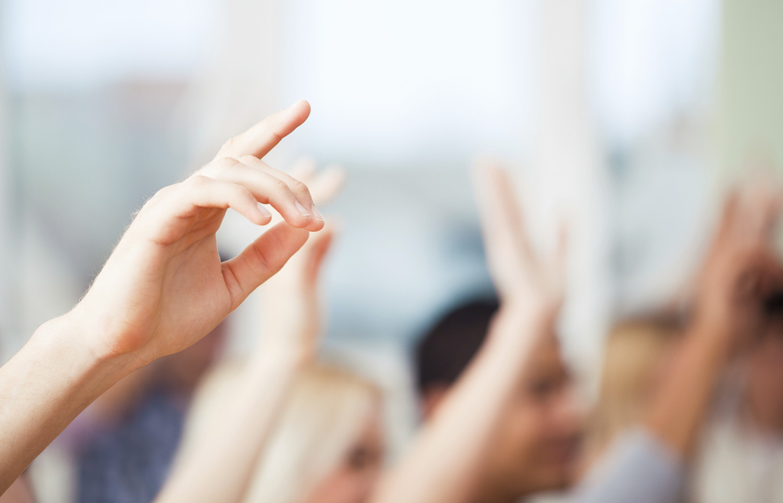 group of people with hands up in the air ready to ask questions